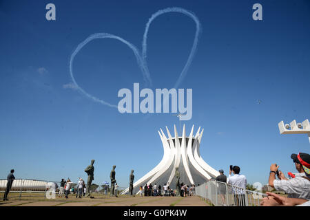 Ein Flugzeug erstellt eine Herzform aus Rauch auf die Kathedrale von Brasilia zu Jahresbeginn die Olympische Fackel-Relais-Kicks off 3. Mai 2016 in Brasilia, Brasilien. Der Fackellauf beginnt eine dreimonatige Reise durch Brasilien, vor der Ankunft für die Olympischen Spiele in Rio De Janeiro im August. Stockfoto