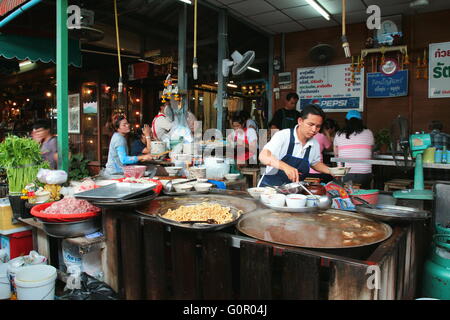 Garküche in Wochenendmarkt Chatuchak, Bangkok. Ein Männer damit beschäftigt, das Essen für die Kunden. Stockfoto