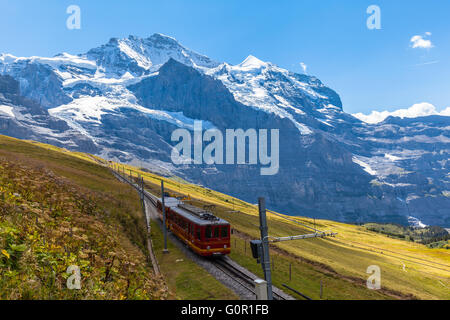 Zug der Jungfraubahn läuft in Richtung Jungfraujoch unter den berühmten Gipfel Jungfrau in der Nähe der Station Eigergletscher auf Berner Obe Stockfoto