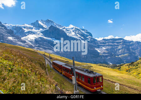 Zug der Jungfraubahn läuft in Richtung Jungfraujoch unter den berühmten Gipfel Jungfrau in der Nähe der Station Eigergletscher auf Berner Obe Stockfoto