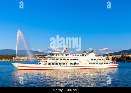 Kreuzfahrtschiff am Genfer See in der Sonne in der Dämmerung, mit dem berühmten Wasserstrahl-Brunnen im Hintergrund, Genf, Schweiz Stockfoto