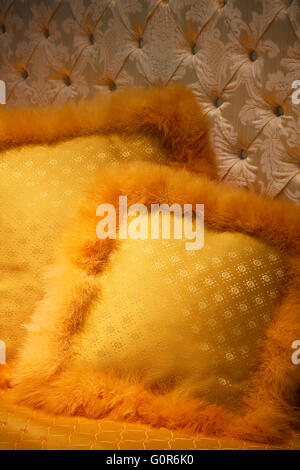 gelbes Kissen mit Flaum auf einem Bett Stockfoto