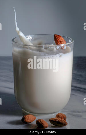 Mandel, Spritzwasser in einem Glas Mandelmilch auf Marmortisch Stockfoto