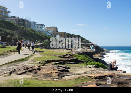 Menschen zu Fuß entlang Sydneys Coastal Walk in Tamarama mit Blick auf den Pazifischen Ozean. Stockfoto