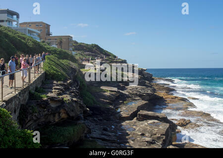 Menschen zu Fuß entlang Sydneys Coastal Walk in Tamarama mit Blick auf den Pazifischen Ozean. Stockfoto