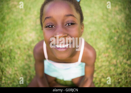 Porträt von einem netten Mischenrennen Mädchen lächelnd und sitzen auf dem Rasen Stockfoto