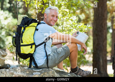 Wanderer, lächelnd und sitzt auf einem Felsen Stockfoto