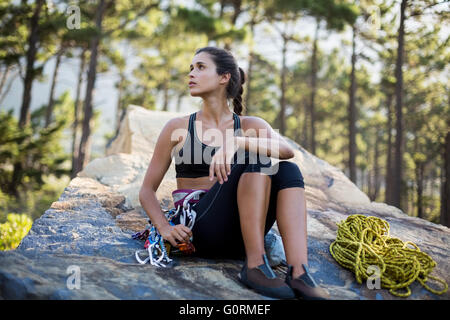 Frau sitzt und posiert mit Kletterausrüstung Stockfoto