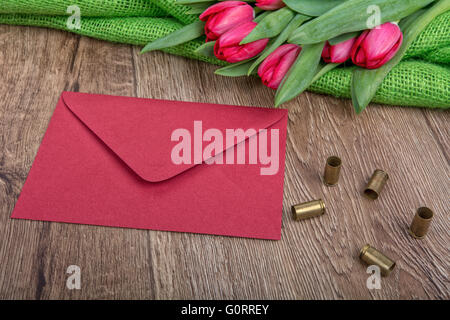 Rote Hülle, Tulpen und Kugeln auf einem hölzernen Hintergrund Stockfoto