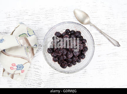 Glasschüssel von Heidelbeeren mit Zucker auf einem rustikalen weiß lackierte Tisch mit einem silbernen Löffel und Serviette von oben geschossen. Stockfoto