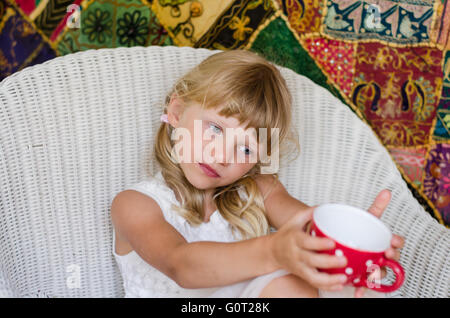 schöne blonde Mädchen kaukasischen sitzen und halten rote Tasse Tee Stockfoto