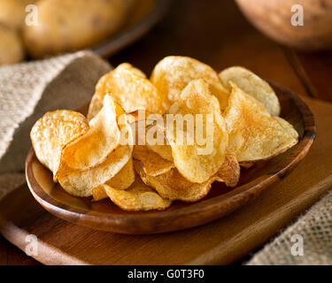 Köstliche hausgemachte Kartoffel-Chips mit Meersalz und schwarzem Pfeffer auf einem rustikalen Hintergrund. Stockfoto