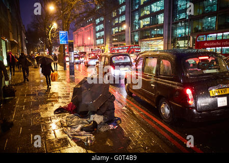 Obdachlose größer betteln Pflaster unter Zelt im Regen nass Regen Wetter kalt A501 Taxis viele vorbei an dunklen Abend Nacht A501 Stockfoto