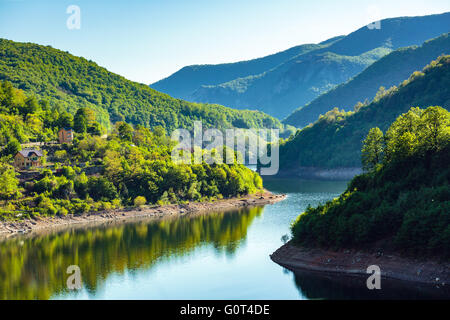 Landschaft mit See zwischen Bergen in Wald bedeckt Stockfoto