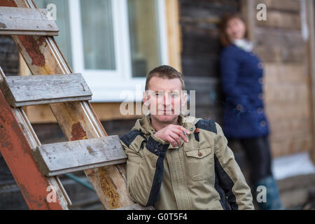 Mann raucht eine Zigarette im Freien stehen, Hintergrund weibliche Silhouette. Stockfoto