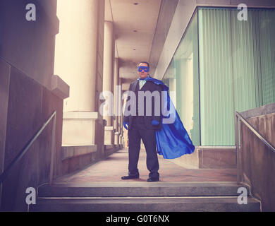 Ein Business-Mann trägt eine blauen Superhelden-Kostüm mit einem Anzug in einer Stadt für eine Karriere Erfolg oder Innovation-Konzept. Stockfoto