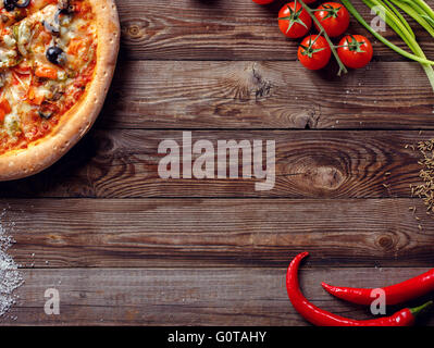 Italienische Pizza mit Tomaten auf einem Holztisch, Ansicht von oben. Stockfoto