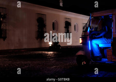 Die motorradfahrer fahren durch eine dunkle Straße in der Nacht in Antigua eine Stadt im zentralen Hochland von Guatemala bekannt für seine gut erhaltenen Spanischen Barock beeinflussten Architektur und ein UNESCO-Weltkulturerbe. Stockfoto