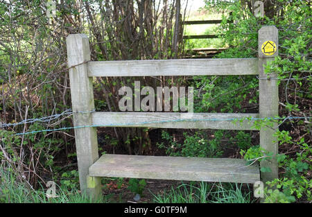 Stil auf einem britischen öffentlichen Wanderweg gelbes Schild mit Stacheldraht, Mai 2016 Stockfoto