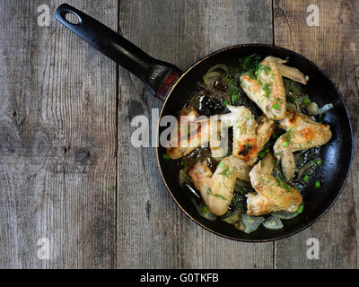 Gebratene Hähnchenflügel in Pfanne auf Holztisch Stockfoto