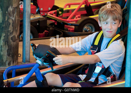 Entzückende junge Kind auf ein Go Cart bei einer Unterhaltung Teil seitlich auf der Suche. Stockfoto