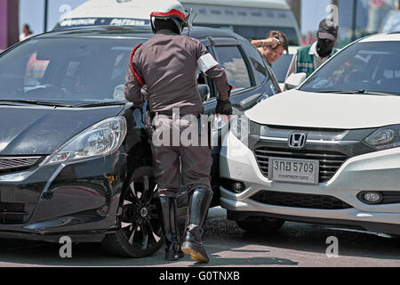 Thailändischer Polizist bei einem Verkehrsunfall mit dem Zusammenstoß zweier Fahrzeuge. Thailand S. E. Asien Stockfoto