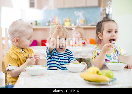 Lustiges kleines Kind spielen und Essen im kindergarten Stockfoto