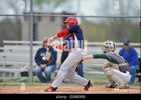 Ein hitter folgt durch auf seine Schwingen, während die Kontaktaufnahme mit einem pitch während einer High School Baseball Spiel. USA. Stockfoto