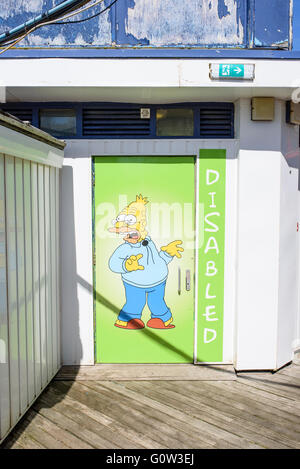 Cartoon-Figur, was Opa Simpson an der Tür des öffentlichen Behindertentoilette auf Central Pier in Blackpool, Lancashire, UK dargestellt Stockfoto