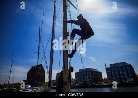 Greifswald, Deutschland. 4. Mai 2016. Herbert Howe klettert den Mast von einem historischen Segelschiff und Bohrinseln den Mast in der Museum-Werft in Greifswald nach dem Boot Winterpause in Greifswald, Deutschland, 4. Mai 2016. Insgesamt 16 historische Segler Boote mit einem Gewicht von 400 kg bis 30 Tonnen werden in das Ostsee-Wasser mit einem mobilen Kran nach ihrer Winterpause aufgehoben. Die meisten der traditionellen Segelschiffe werden Fahrten auf der Ostsee oder dem Bodden Gewässern in den nächsten Tagen machen. Foto: JENS Büttner/Dpa/Alamy Live News Stockfoto