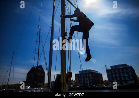 Greifswald, Deutschland. 4. Mai 2016. Herbert Howe klettert den Mast von einem historischen Segelschiff und Bohrinseln den Mast in der Museum-Werft in Greifswald nach dem Boot Winterpause in Greifswald, Deutschland, 4. Mai 2016. Insgesamt 16 historische Segler Boote mit einem Gewicht von 400 kg bis 30 Tonnen werden in das Ostsee-Wasser mit einem mobilen Kran nach ihrer Winterpause aufgehoben. Die meisten der traditionellen Segelschiffe werden Fahrten auf der Ostsee oder dem Bodden Gewässern in den nächsten Tagen machen. Foto: JENS Büttner/Dpa/Alamy Live News Stockfoto