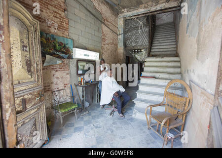 3. Mai 2016 - Havanna, Kuba - während Sie buchstäblich vor der Haustür geht es um die größte Modenschau in der kubanischen Geschichte passieren die Chanel '' Kreuzfahrt '' Modenschau, Barbier Juan Carlos gibt einen Haarschnitt, seinen Mandanten in seinem Haus, das auf einer schönen Bäumen gesäumten Prado-Promenade in Havanna, Kuba, 3. Mai, 2016. Kubas goldene Ära, als es ein reicher Hafen war, erbaute sind kolonialen Kolonnaden und eleganten Art-Deco-Gebäuden auf beiden Seiten des Boulevards jetzt in verschiedenen Zuständen von Disrepair obwohl einige renoviert werden. Polizei blockiert das ganze Gebiet in den Stunden vor der Show keepi Stockfoto