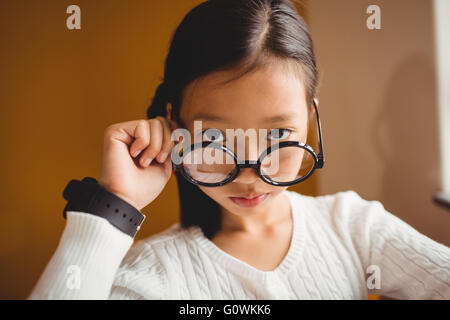 Schulkind hält ihre Brille Stockfoto