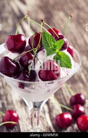 Gefrorenen Fruchtdessert Softeis mit süßen Kirschen im Martiniglas auf shabby chic Hintergrund an der Spitze Stockfoto