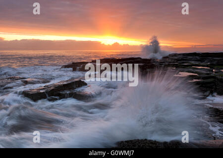 Wellen auf den Felsen am Beacon Point im Newbiggin By The Sea an der Nordost-Küste bei Sonnenaufgang. Stockfoto