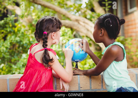 Rückansicht der beiden Mädchen auf einem Globus zeigen Stockfoto