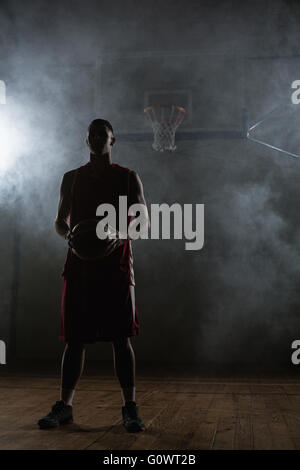 Porträt von einem Basketball-Spieler, einen Ball in den Händen hält Stockfoto