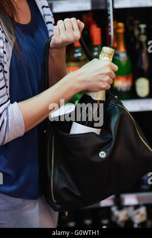 Frau, indem eine Flasche Wein in ihrer Tasche Stockfoto