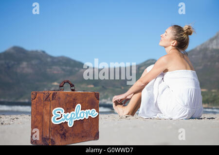 Zusammengesetztes Bild Inhalt Blondine im weißen Kleid am Strand sitzen Stockfoto