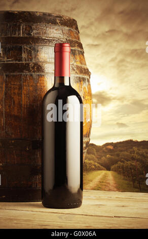 rote Flasche und Wodden Weinfass, Weinberg im Hintergrund Stockfoto