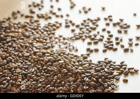 Jede Menge Kaffeebohnen verstreut auf Holztisch, unscharf Hintergrund mit selektiven Fokus Stockfoto