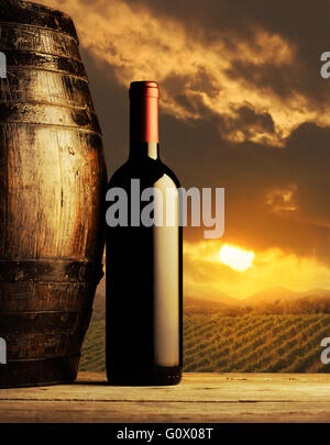rote Flasche und Wodden Weinfass, Weinberg im Hintergrund Stockfoto