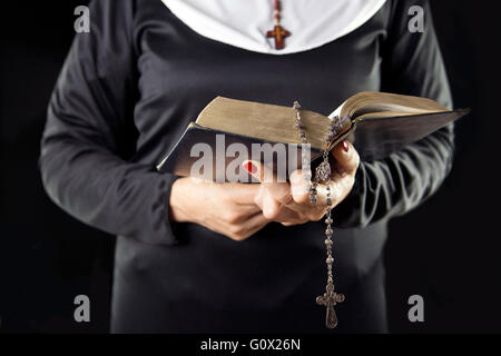 Nonne Hände halten Sie Buch der Bibel über grauen Hintergrund Stockfoto