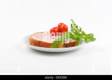 Stapel von Schinkenscheiben, Cherry-Tomaten und Dill auf weißen Teller Stockfoto
