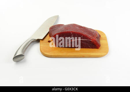 Stück rohes Rindfleisch Fleisch und scharfe Messer auf Holzbrett Stockfoto