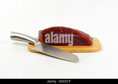 Stück rohes Rindfleisch Fleisch und scharfe Messer auf Holzbrett Stockfoto