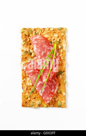 Kürbiskern-Cracker mit trockene Salami und Schnittlauch auf weißem Hintergrund Stockfoto