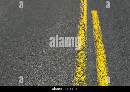 Doppelte gelbe Grunge-Linie auf Asphaltstraße. Stockfoto