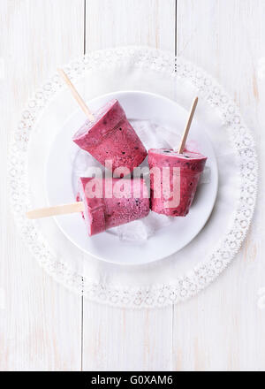 Hausgemachte Obst schwarze Johannisbeeren Eis am Stiel auf weißem Holz Hintergrund, Ansicht von oben Stockfoto