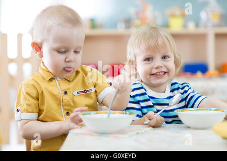 Zwei lustige lächelnden kleinen Kinder Essen im kindergarten Stockfoto